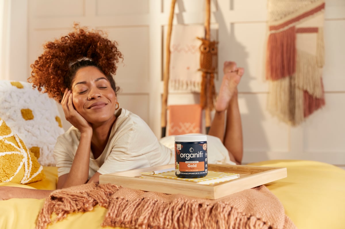 Model smiling on bed with product