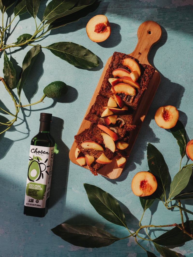 Platter of peach bread surrounded by peaches and Chosen Foods avocado oil bottle