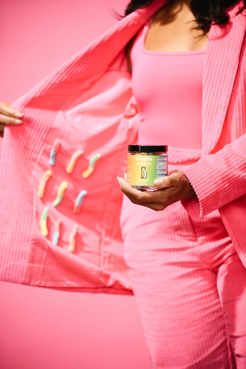 Model showing inside of pink suit full of CBD gummy worms with product in other hand