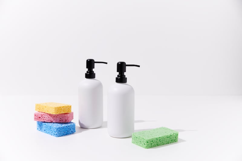 White soap dispenser with sponges on white background
