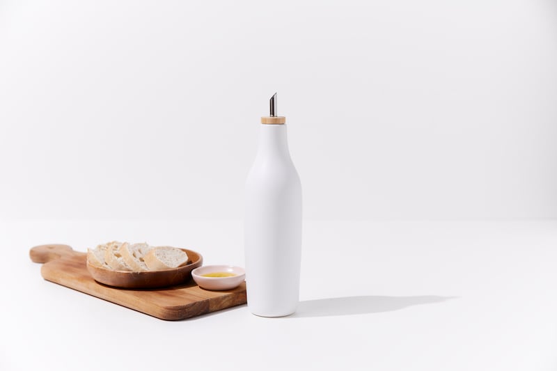 White olive oil dispenser with bread on white background