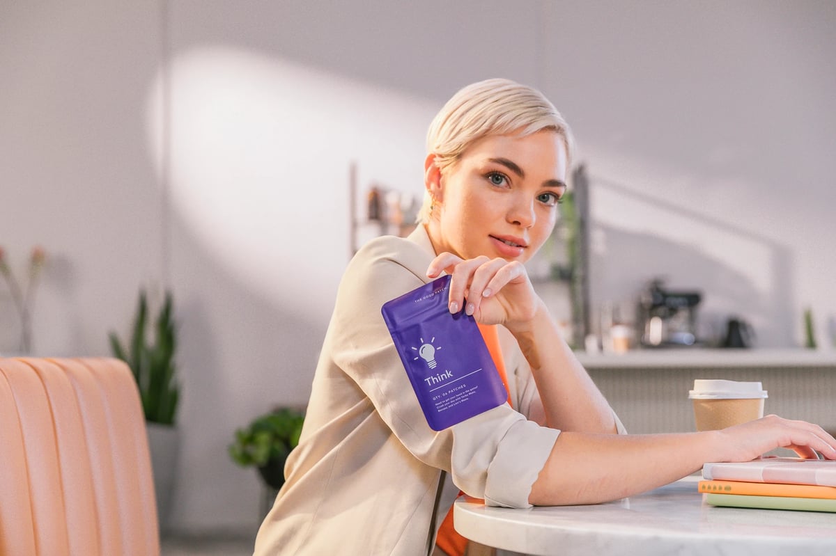 Model holding The Good Patch product at coffee shop